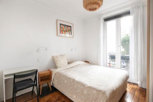 une chambre avec un lit, un bureau et une fenêtre dans l'établissement T2 Spacieux à Paris 19e - Parc de la Villette, à Paris