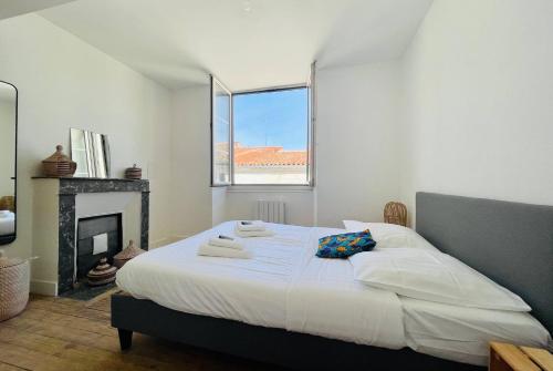 - une chambre blanche avec un grand lit et une cheminée dans l'établissement Le Grand Minage - Hypercentre Wifi, à La Rochelle