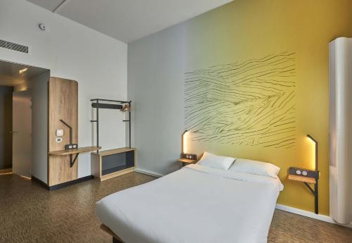 a bedroom with a white bed and a yellow wall at B&B HOTEL Ouistreham in Ouistreham