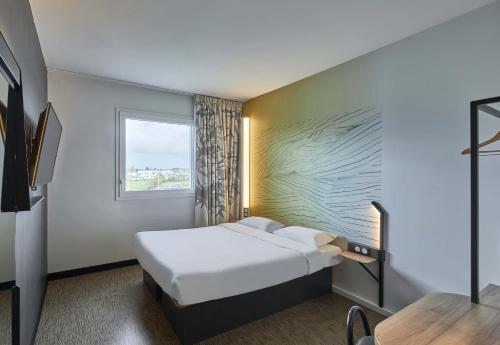 a hotel room with a bed and a window at B&B HOTEL Ouistreham in Ouistreham