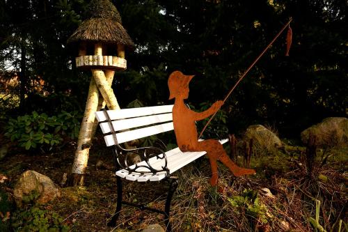 a statue of a person on a bench next to a bird house at Hillmers Hoff PensionRestaurant in Undeloh