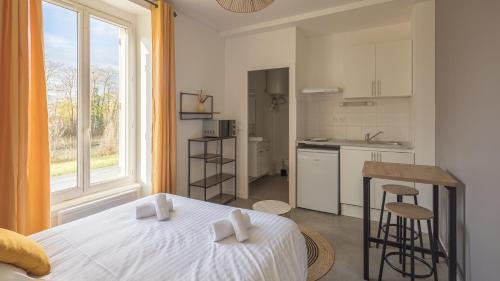 une chambre blanche avec un lit et une cuisine dans l'établissement Sunshine - Appartement neuf - parking, à Châlons-en-Champagne