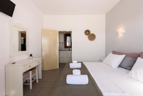 a white bedroom with a bed and a desk at Archipelagos Studios in Naousa
