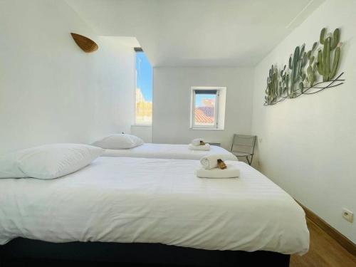deux lits dans une chambre aux murs blancs dans l'établissement La Cabane - T3 Avec Terrasse Plein Centre Ville LR, à La Rochelle