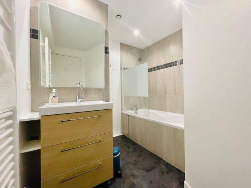 une salle de bain avec un lavabo, une baignoire et un miroir dans l'établissement La Cabane - T3 Avec Terrasse Plein Centre Ville LR, à La Rochelle