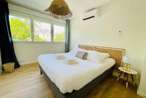 une chambre avec un lit avec des draps blancs et une fenêtre dans l'établissement L Escapade Rochelaise - Wifi & Balcon, à La Rochelle