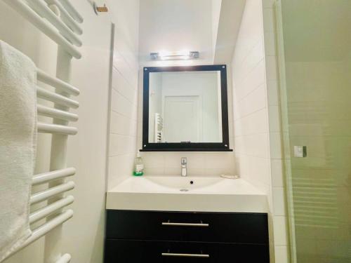 une salle de bain blanche avec un lavabo et un miroir dans l'établissement La Petite Genette, à La Rochelle