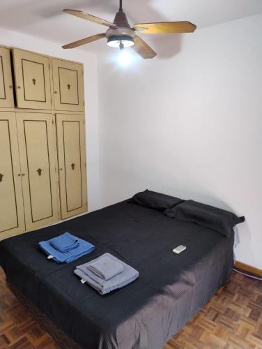 a bedroom with a black bed with a ceiling fan at Departamento céntrico in Concepción del Uruguay