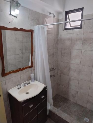 a bathroom with a sink and a shower with a mirror at Departamento céntrico in Concepción del Uruguay