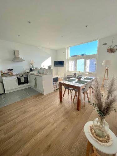 Il comprend un grand salon avec une table et une cuisine. dans l'établissement L'îlot vert, à Wimereux