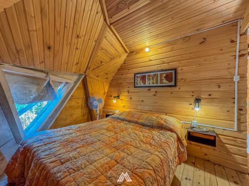 a bedroom with a bed in a wooden cabin at SAGRADAS de LA PALOMA in La Paloma