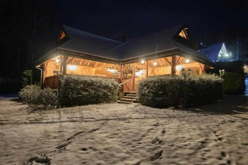 a large wooden house with snow on the ground at Villa Biesisko Przysłup Cisna in Cisna