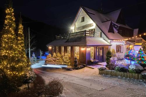 a house decorated with christmas lights and a christmas tree at Villa Biesisko Przysłup Cisna in Cisna