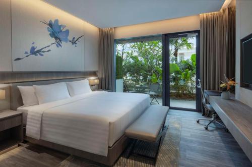 a bedroom with a large white bed and a balcony at Dusit Thani Laguna Singapore in Singapore