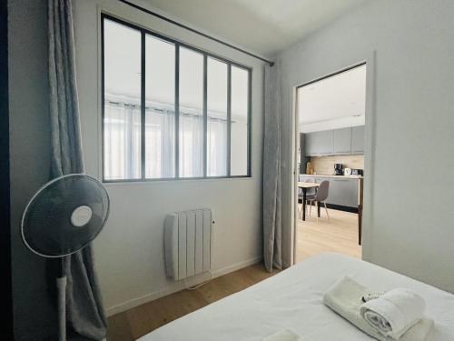 une chambre avec un lit et une grande fenêtre dans l'établissement La Petite Fonderie 2eme etage - Bel Appt Centre Ville Lr Wifi, à La Rochelle