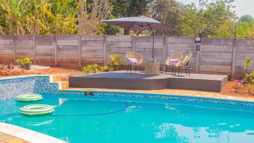een zwembad met twee stoelen en een parasol bij Casa Linda in Harare