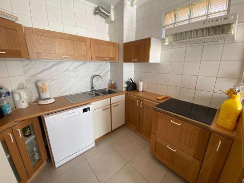 - une cuisine avec des placards en bois et un lave-vaisselle blanc dans l'établissement T3 pour 6 pers, vue mer et montagne, terrasse, parking, proche plage, Le Barcarès - FR-1-81-550, au Barcarès