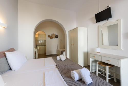 a white room with a bed and a desk and a mirror at Archipelagos Studios in Naousa