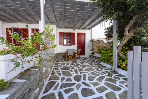 a patio with a stone floor and a red door at Archipelagos Studios in Naousa