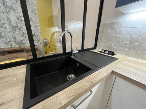 - une cuisine avec un évier noir et un miroir dans l'établissement Centre ville - t2 de standing, à La Rochelle