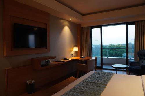 une chambre d'hôtel avec un lit, un bureau et une fenêtre dans l'établissement Kiranshree Grand, à Guwahati