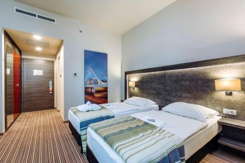 a hotel room with two beds and a painting on the wall at ETO Park Hotel Business & Stadium in Győr