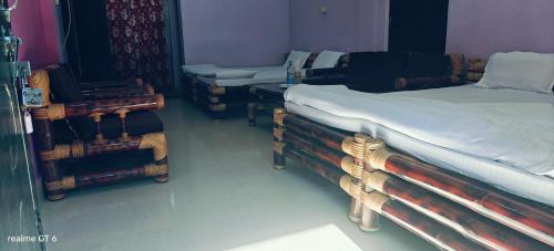 a room with two beds and chairs in it at Niribili Homestay in Majuli