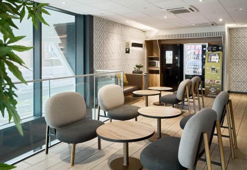 a waiting room with tables and chairs in a restaurant at B&B HOTEL Paris Porte de Bagnolet in Bagnolet