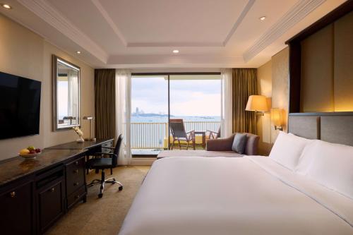 a hotel room with a large bed and a desk at Dusit Thani Pattaya in North Pattaya