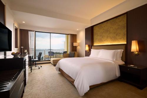 a bedroom with a large white bed and a piano at Dusit Thani Pattaya in North Pattaya