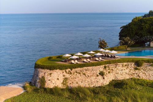 a group of chairs and umbrellas next to the ocean at Dusit Thani Pattaya in North Pattaya