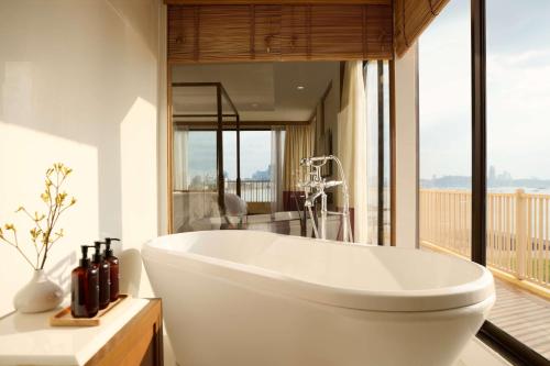 a white bath tub in a bathroom with a balcony at Dusit Thani Pattaya in North Pattaya