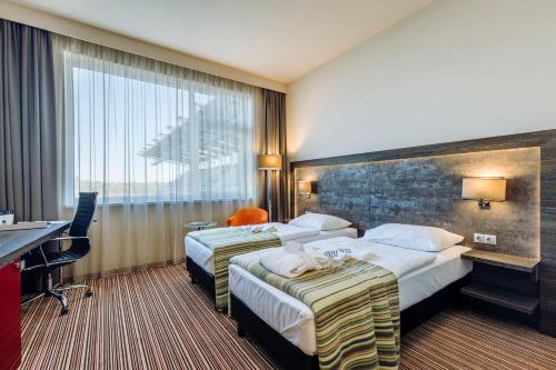 a hotel room with two beds and a desk at ETO Park Hotel Business & Stadium in Győr