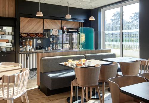 a restaurant with tables and chairs and a counter at B&B HOTEL Saint-Denis Porte de Paris in Saint-Denis