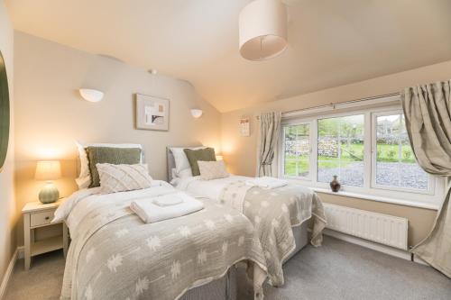 two beds in a room with a window at Central Malham Wellbeing Escape, 5-bed house with yoga studio in Malham