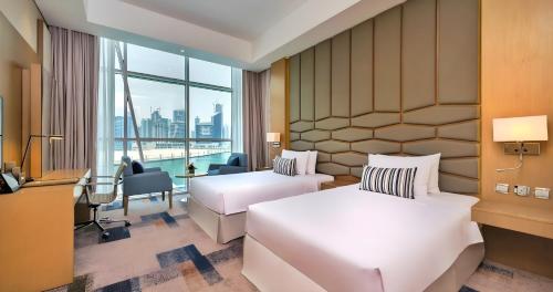 a hotel room with two beds and a window at Canal Central Hotel Business Bay in Dubai