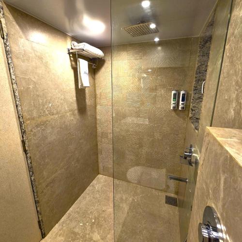 a bathroom with a shower with a glass door at Hotel Auris & Banquets, Mumbai International Airport in Mumbai