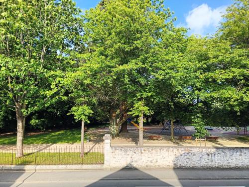 une clôture avec des arbres dans un parc à côté d'une rue dans l'établissement Studio proche centre-ville, à Vitré