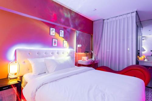 a bedroom with a white bed and a purple wall at Cosy Hotel in Ho Chi Minh City