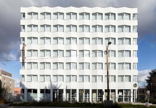 a white building with a street light in front of it at B&B HOTEL Massy Gare TGV in Massy