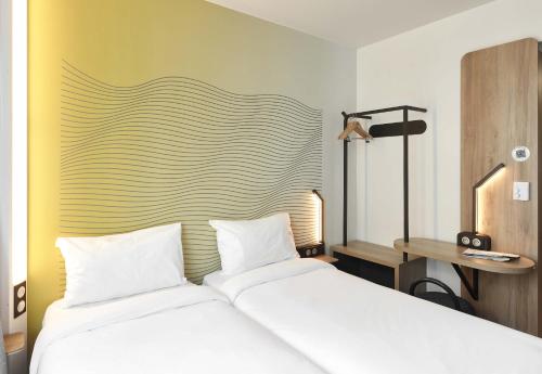 a bedroom with a white bed and a yellow wall at B&B HOTEL Massy Gare TGV in Massy