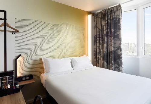a bedroom with a large white bed and a window at B&B HOTEL Massy Gare TGV in Massy