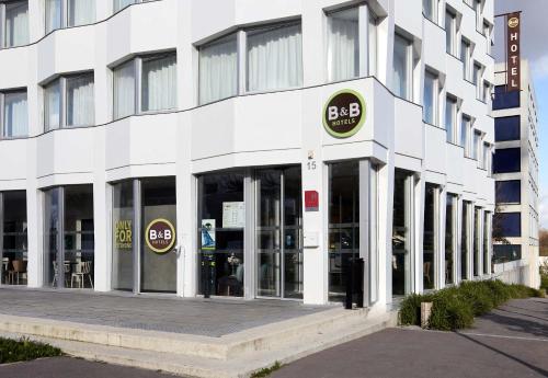 a white building with a bbq sign on it at B&B HOTEL Massy Gare TGV in Massy