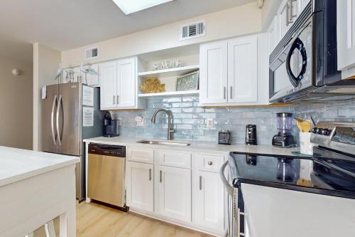 a kitchen with white cabinets and a stainless steel refrigerator at Seaside Beach & Racquet Club #4611 in Orange Beach