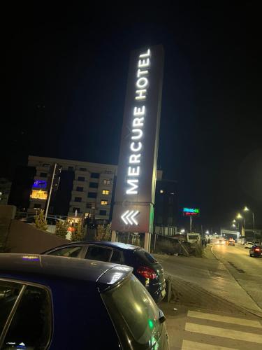 a sign for a hotel with cars parked in a parking lot at Kleon Apartament in Pristina