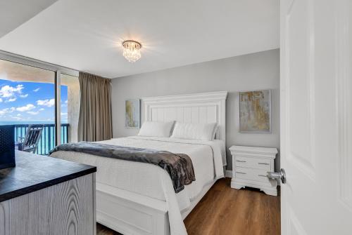 a white bedroom with a bed and a balcony at 4BR Oceanfront Corner Condo NMB in Myrtle Beach
