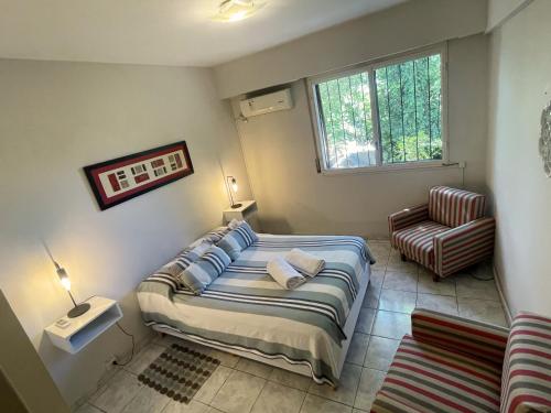 a bedroom with a bed and a chair at Departamento Frente al Parque in Villa Marini