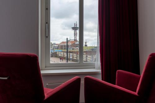 a room with two red chairs and a window at Boutique Hotel Maldegem in Vlissingen