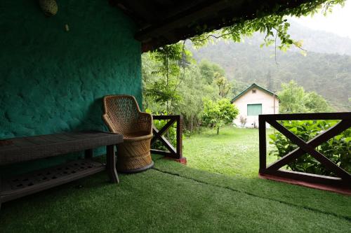 a bench sitting on the porch of a house with a view at Thehraav By The River - Mudhouse Odyssey, Tirthan Valley in Banjār
