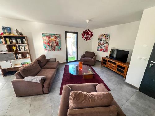 un salon avec un canapé et une télévision dans l'établissement L'olivette de Sommières, belle maison calme à quelques minutes du centre ville historique, à Sommières